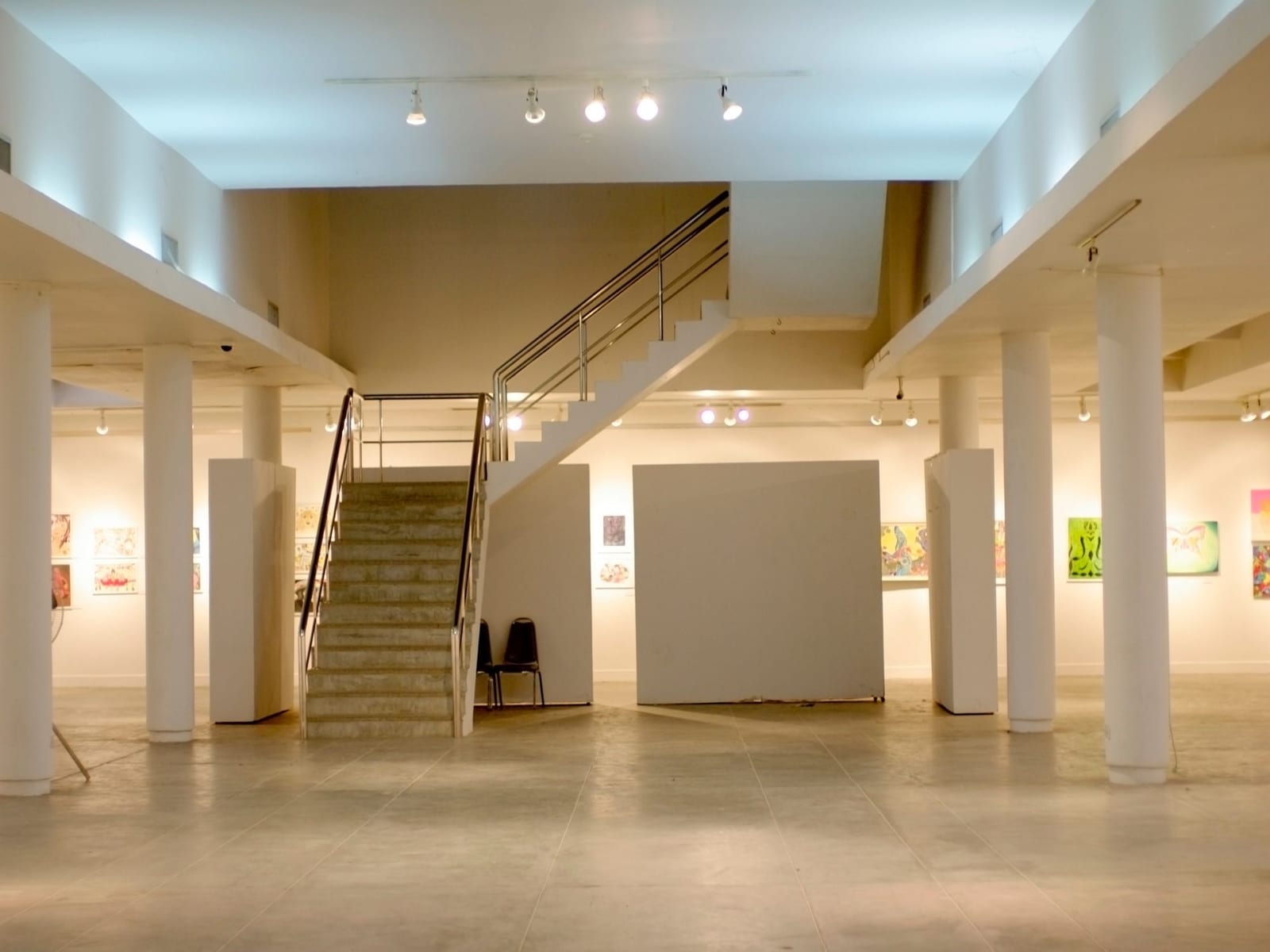 An empty gallery floor with works hung along the walls, temporary partitions, and nobody in the room.