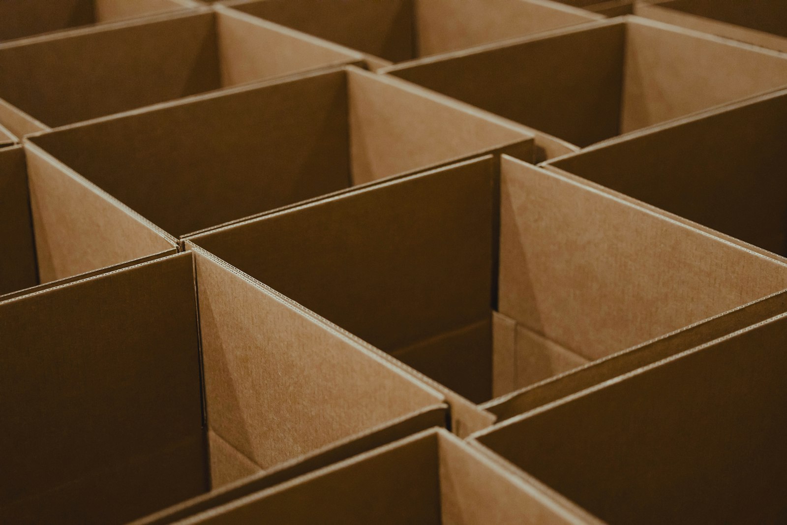 Rows of empty flat brown cardboard boxes standing open, seen from above at an angle.