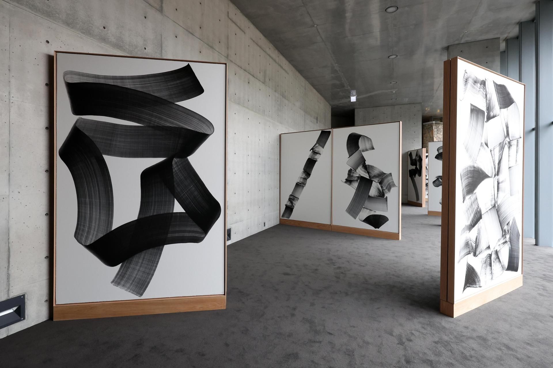A concrete lobby at Museum SAN hung with framed Brushstroke works by Lee Bae, each a single wide black gesture on pale paper.